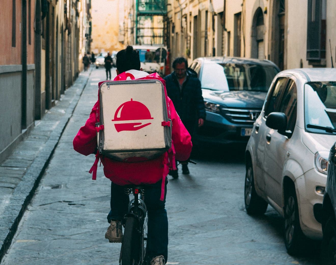 A delivery courier cycling through a city