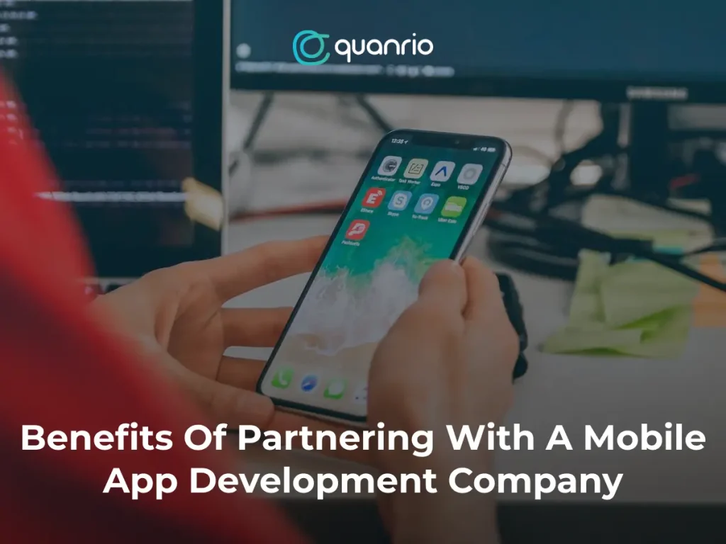 A person holding a smartphone with various app icons visible, with the text "Benefits Of Partnering With A Mobile App Development Company" overlaid on the image.