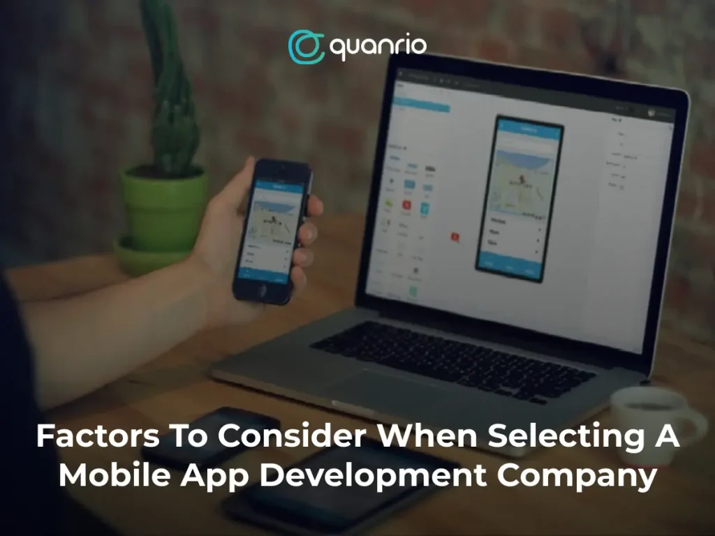 A person holding a smartphone displaying a mobile app, with a laptop showing the same app on a table, accompanied by the text "Factors To Consider When Selecting A Mobile App Development Company."